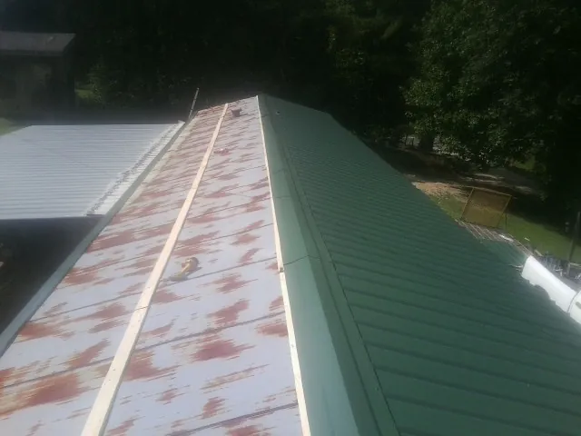 Old rusted panels beside newly installed green metal roofing — Wind Damage Roof Repair by Roofing Brothers in Blair