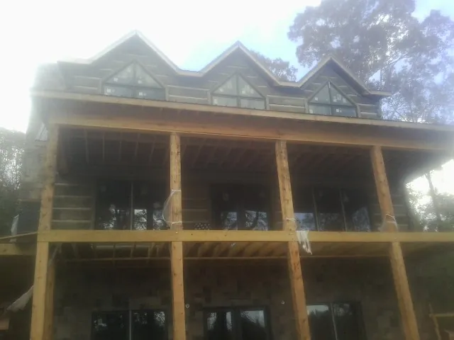 Dormers and porch framing on a large log home under construction — Roof Coating work by our crew in Blair